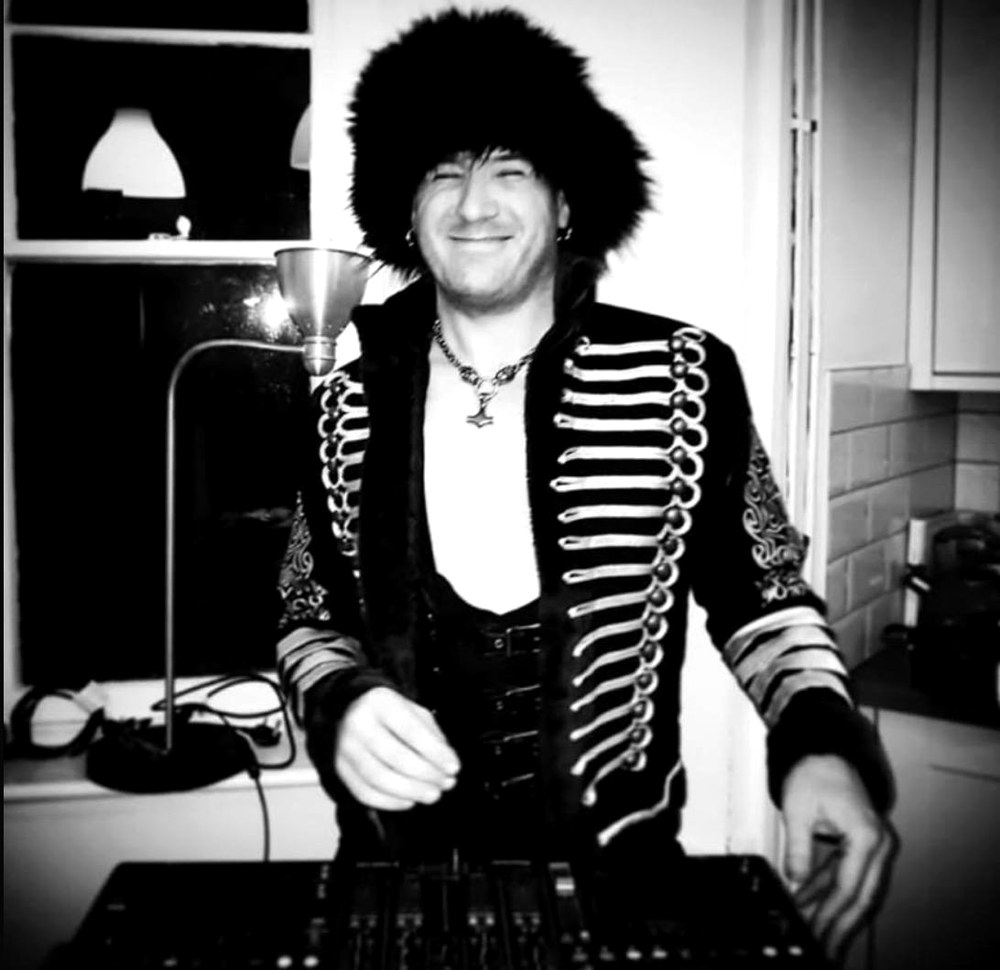 DJ Ed Thorman behind the decks in a fur hat and braided military jacket