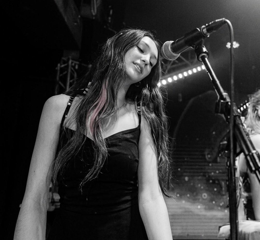 Eva singing into a microphone under stage lights