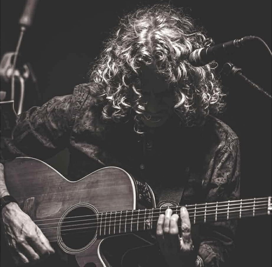Ian Luther playing acoustic guitar at a microphone