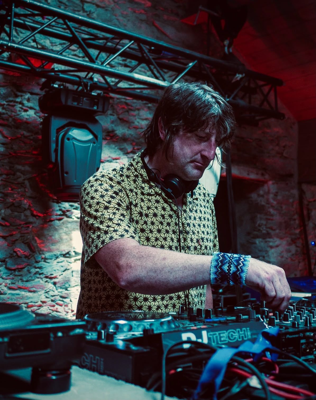 Zac Toucan DJing in a stone-walled venue under teal and red lighting